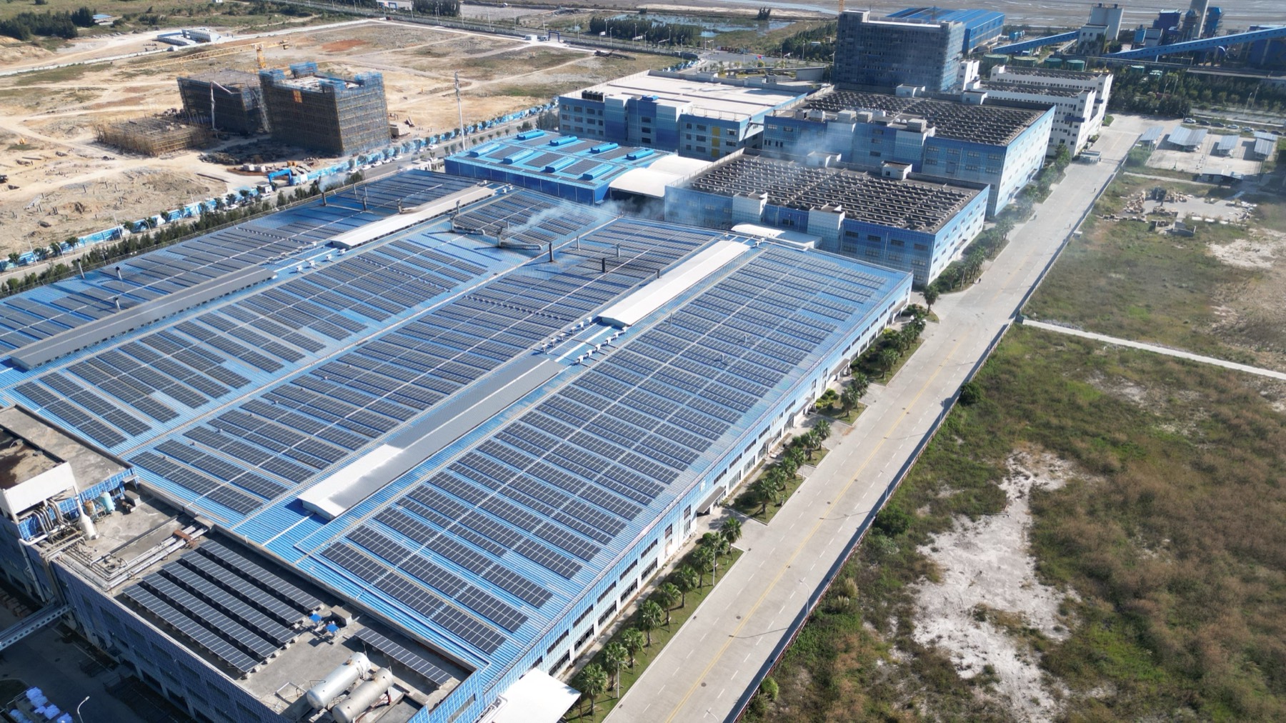 Aerial view of an industrial complex with rooftop solar arrays covering its warehouses